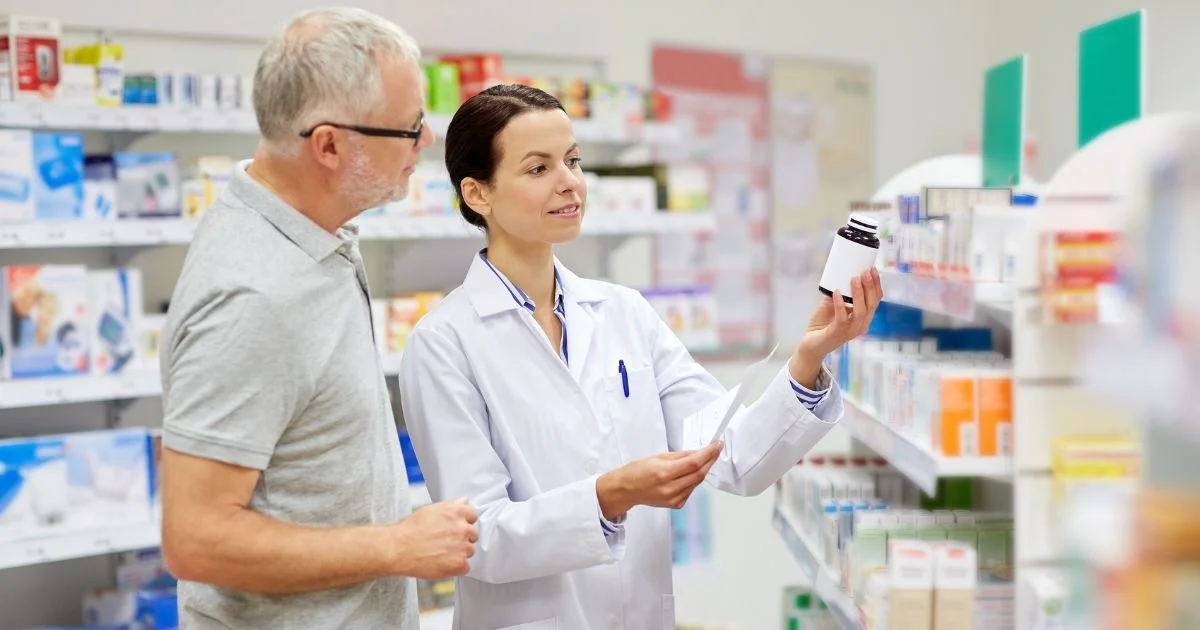 Pharmacist assisting a senior man with medication in a pharmacy.